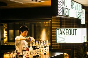 京都的住宿－樱花台画廊酒店，一个人在酒吧准备饮料,并配上瓶装葡萄酒