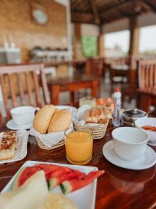 a wooden table with breakfast foods and orange juice at Vila Jeri Hotel in Jericoacoara