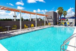 a swimming pool with chairs and tables on a building at Home2 Suites By Hilton Wildwood The Villages in Wildwood