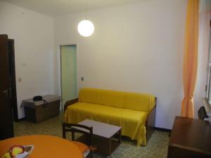 sala de estar con sofá amarillo y mesa en Monolocale n°1 vicino al centro con dehor, en Laigueglia