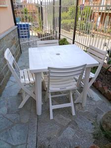 una mesa blanca y sillas sentadas junto a una valla en Monolocale n°1 vicino al centro con dehor, en Laigueglia