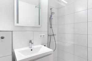 Un baño blanco con lavabo y ducha. en Apartment Schwarzwald, en Schönwald 21 fotos más