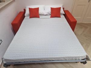 Una cama con dos almohadas rojas encima. en B&B Colaci, en Alessano