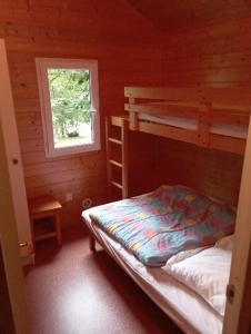 une chambre avec deux lits superposés et une fenêtre dans l'établissement Chalet les Hameaux du Perrier, à Lissac-sur-Couze