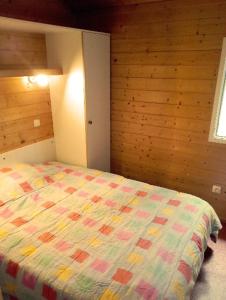 a bedroom with a bed with a colorful quilt at Chalet les Hameaux du Perrier in Lissac-sur-Couze
