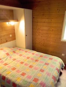 une chambre avec un lit avec une couette colorée dans l'établissement Chalet les Hameaux du Perrier, à Lissac-sur-Couze