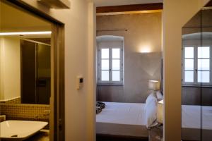 Schlafzimmer mit einem Bett, einem Waschbecken und einem Spiegel in der Unterkunft Resort Faro di Punta Fenaio in Campese