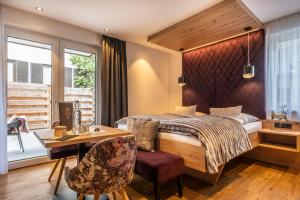 Dorfkrug Kaprun - Luxury Suites & Appartements by SFL في كابرون: غرفة نوم بسرير وطاولة وكراسي