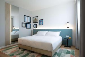 a bedroom with a large white bed and a mirror at Hampton by Hilton Rome North Fiano Romano in Fiano Romano