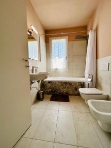 a bathroom with a tub and a sink and a toilet at Kibilù - Via Galvani con parcheggio e giardino privato in Ispra