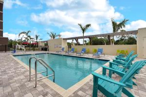 una piscina con sillas azules y un tobogán en Home2 Suites By Hilton Lakewood Ranch en Bradenton
