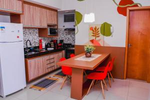 a kitchen with a wooden table and red chairs at Acomodação Extraordinária em sua viagem - LoftFelau in Cuiabá
