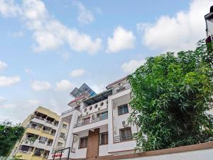 un edificio blanco con un árbol delante en OYO Home Saraswati Niwas Vadgaon Budruk Near Fun Time Multiplex en Pune