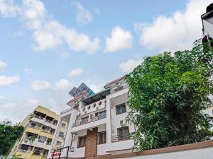 OYO Home Saraswati Niwas Vadgaon Budruk Near Fun Time Multiplex في بيون: مبنى ابيض امامه شجرة