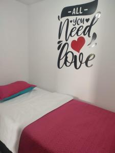 a bed with a sign that says all you need is love at Delicioso cafecito! in Armenia