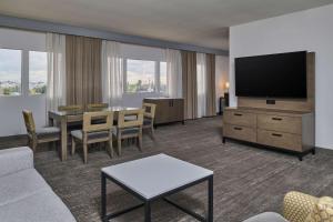 a living room with a couch and a table with a television at Doubletree by Hilton Buena Park in Buena Park