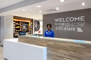 a woman standing at a counter in a store at Hampton Inn Kansas City Southeast, Mo in Kansas City