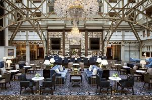 um átrio com um lustre e mesas e cadeiras em Waldorf Astoria Washington DC em Washington