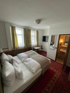 1 dormitorio con 1 cama grande con almohadas blancas en Hotel Garni Ratstube en Bad Urach