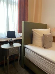 a bedroom with a bed and a table with a lamp at Hotel Garni Ratstube in Bad Urach +22 photos