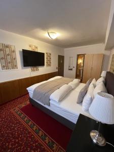 a hotel room with a large bed and a flat screen tv at Hotel Garni Ratstube in Bad Urach