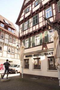 un hombre montando en monopatín frente a un restaurante de hotel en Hotel Garni Ratstube en Bad Urach