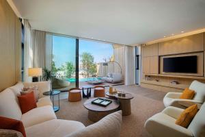 sala de estar con muebles blancos y TV de pantalla plana en Katara Hills Doha, Lxr Hotels & Resorts en Doha