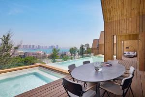a patio with a table and chairs next to a swimming pool at Katara Hills Doha, Lxr Hotels & Resorts in Doha