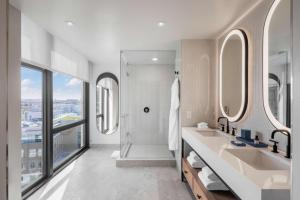 a bathroom with a shower and two sinks and mirrors at The Morrow Washington Dc, Curio Collection By Hilton in Washington