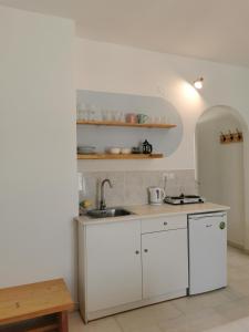 una cocina con armarios blancos y fregadero en KR Apartments, en Aliki