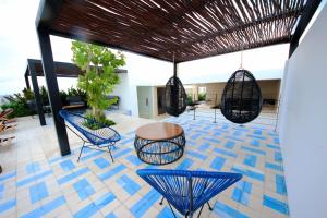 eine Terrasse mit blauen Stühlen, einem Tisch und Schaukeln in der Unterkunft Spacious Studio, incredible rooftop with sea view in Playa del Carmen
