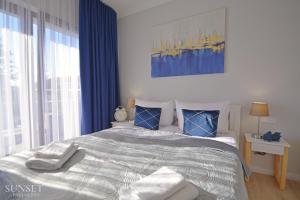 sypialnia z dużym łóżkiem z niebieskimi zasłonami w obiekcie Sunset Apartments - Kormoran - Plaża 300m w Świnoujściu +19 zdjęć