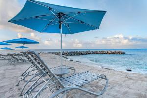 two chairs and an umbrella on a beach at Hilton Vacation Club Flamingo Beach Sint Maarten in Simpson Bay