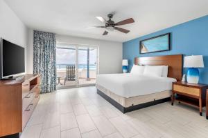 a bedroom with a bed and a television and a balcony at Hilton Vacation Club Flamingo Beach Sint Maarten in Simpson Bay