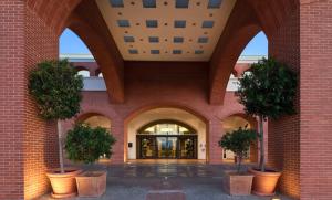 a building with three potted trees in a courtyard at Domes Lake Algarve, Autograph Collection in Vilamoura