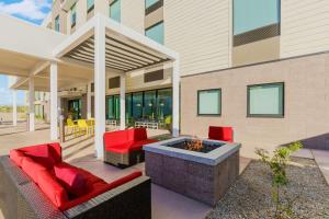 a patio with red chairs and a fire pit at Home2 Suites By Hilton North Scottsdale Near Mayo Clinic in Scottsdale