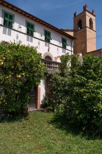 un bâtiment avec une tour d'horloge et quelques buissons dans l'établissement Villa Castel del Monte, à Pescia