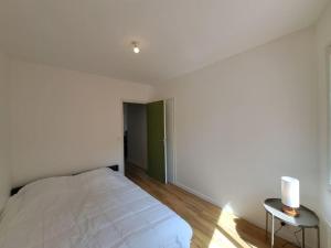 a white bedroom with a bed and a table at Milan - Au milieu des Maisons de Champagne in Reims
