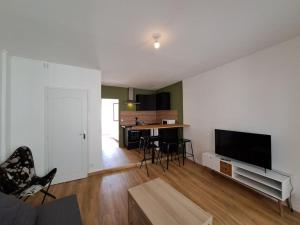 ein Wohnzimmer mit einem Sofa und einem TV sowie eine Küche in der Unterkunft Milan - Au milieu des Maisons de Champagne in Reims