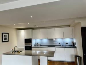 una cucina con armadi bianchi e piano di lavoro di Modern 1bedflat Kensington a Londra