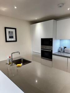a white kitchen with a sink and a stove at Modern 1bedflat Kensington in London