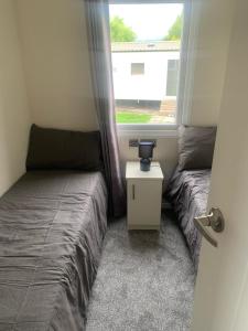 2 Betten in einem kleinen Zimmer mit Fenster in der Unterkunft 136, Port Haverigg in Millom