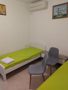 a bedroom with a green bed and two chairs at Vila Sipovac in Budva