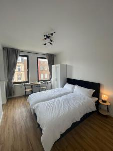 a bedroom with a large white bed and two windows at Cozy and central Apartment Lübeck in Lübeck