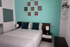 1 dormitorio con 1 cama y algunas fotos en la pared en Piso en San Fernando (Cádiz), en San Fernando