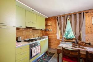 une cuisine avec des placards verts, une table et une table dans l'établissement Maison Grange 4, à Gressan