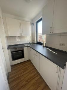 a kitchen with white cabinets and a black counter top at Cozy and central Apartment Lübeck in Lübeck