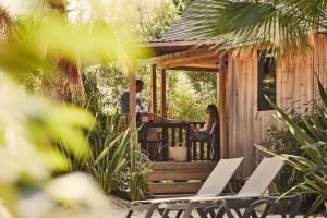 a man and woman sitting on the porch of a cabin at Les Prairies de la Mer in Grimaud