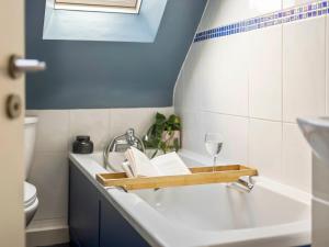 a bathroom with a bath tub with a book and a glass of wine at The Loft - A Stylish Holiday Property in Weymouth with Sea View and Parking in Weymouth +25 photos