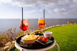 Resort Faro di Punta Fenaio في كامبيس: طاولة مع كأسين من النبيذ وصحن من الطعام
